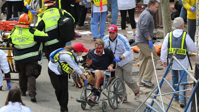 An injured person is taken away from the scene in a wheelchair.
