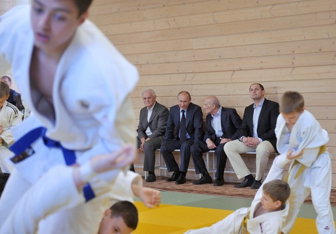 Tổng thống Putin (hàng sau, thứ hai từ trái qua) cùng cựu huấn luyện viên judo của ông, Anatoly Rakhli, theo dõi một nhóm võ sinh tập luyện khi ông đến thăm trường thể thao ở St. Petersburg tháng 5/2013.