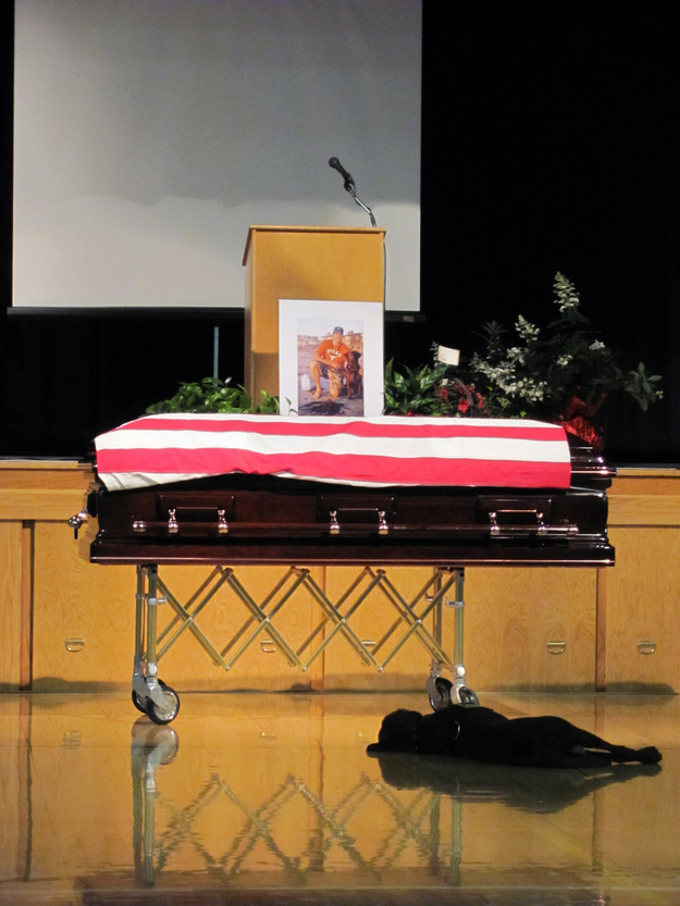     Chú chó Hawkeye nằm trước quan tài của chủ mình trong suốt lễ tang