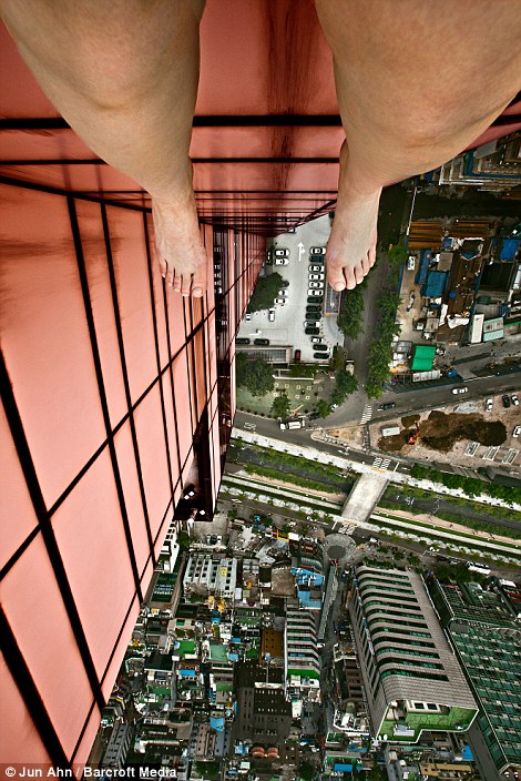 In some of the daring artworks, viewers are afforded stomach-churning vertical views of Jun's feet dangling hundreds of feet above the bustling city streets below
