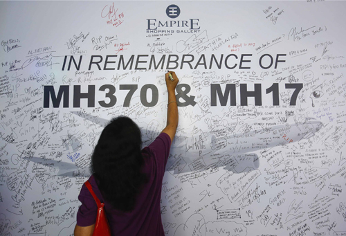 Một người phụ nữ viết lên bảng tưởng niệm các nạn nhân trên hai chuyến bay của Malaysia MH370 và MH17 ở Subang Jaya, ngoại ô Kuala Lumpur. Ảnh: Reuters