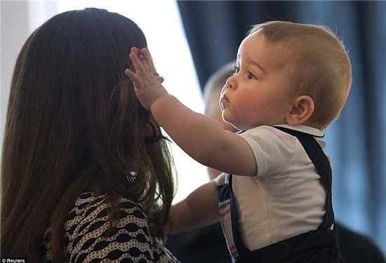The young royal appeared more interested with his mother's hair than the other children and was seen gently pulling her brunette tresses away from the Duchess' face