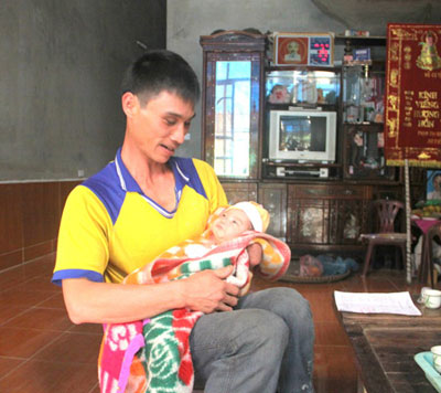 Anh Nguyễn Văn Bắc bế cô con gái nhỏ đã sớm mồ côi mẹ