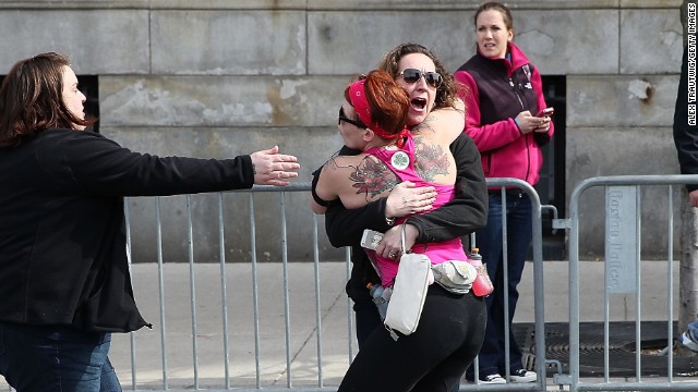 A runner embraces another woman on the marathon route near Kenmore Square.